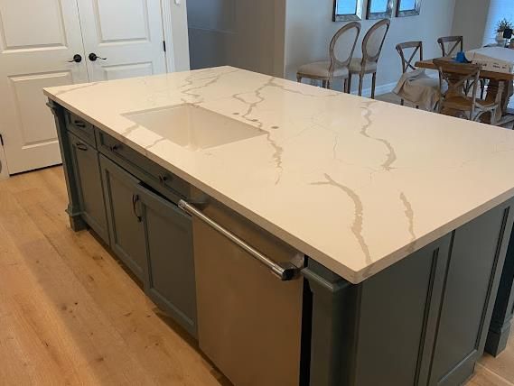 Calacatta quartz island with sage cabinets by AZ Elite Granite