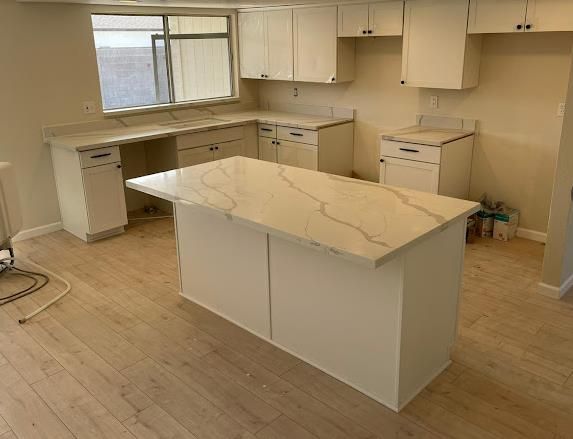 Calacatta quartz kitchen with white cabinets and light wood floor by AZ Elite Granite
