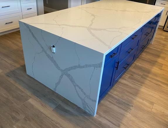 Calacatta quartz waterfall island on navy cabinetry — a GC Stone Fabricators install in Dallas